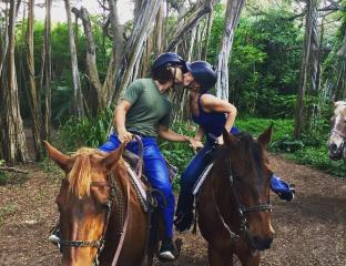 A couple on horses kissing in the woods